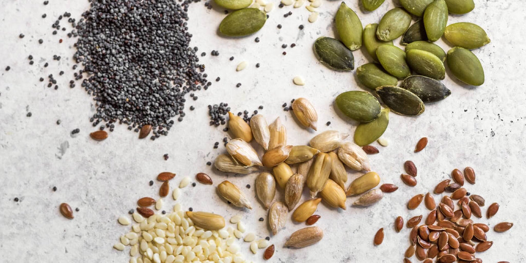 Blanding af økologiske frø fra Danish Granola Company på en køkkenbord. Vi kan se chiafrø, solsikkefrø, græskarkerner og nogle andre frø.