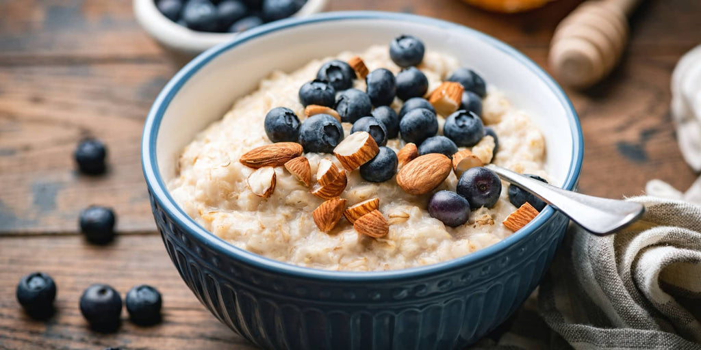 Grødskål med økologiske og glutenfri havregryn med tørret frugt. Skålen er toppet med mandler og blåbær. Skålen er blå med minimalistisk skandinavisk stil.