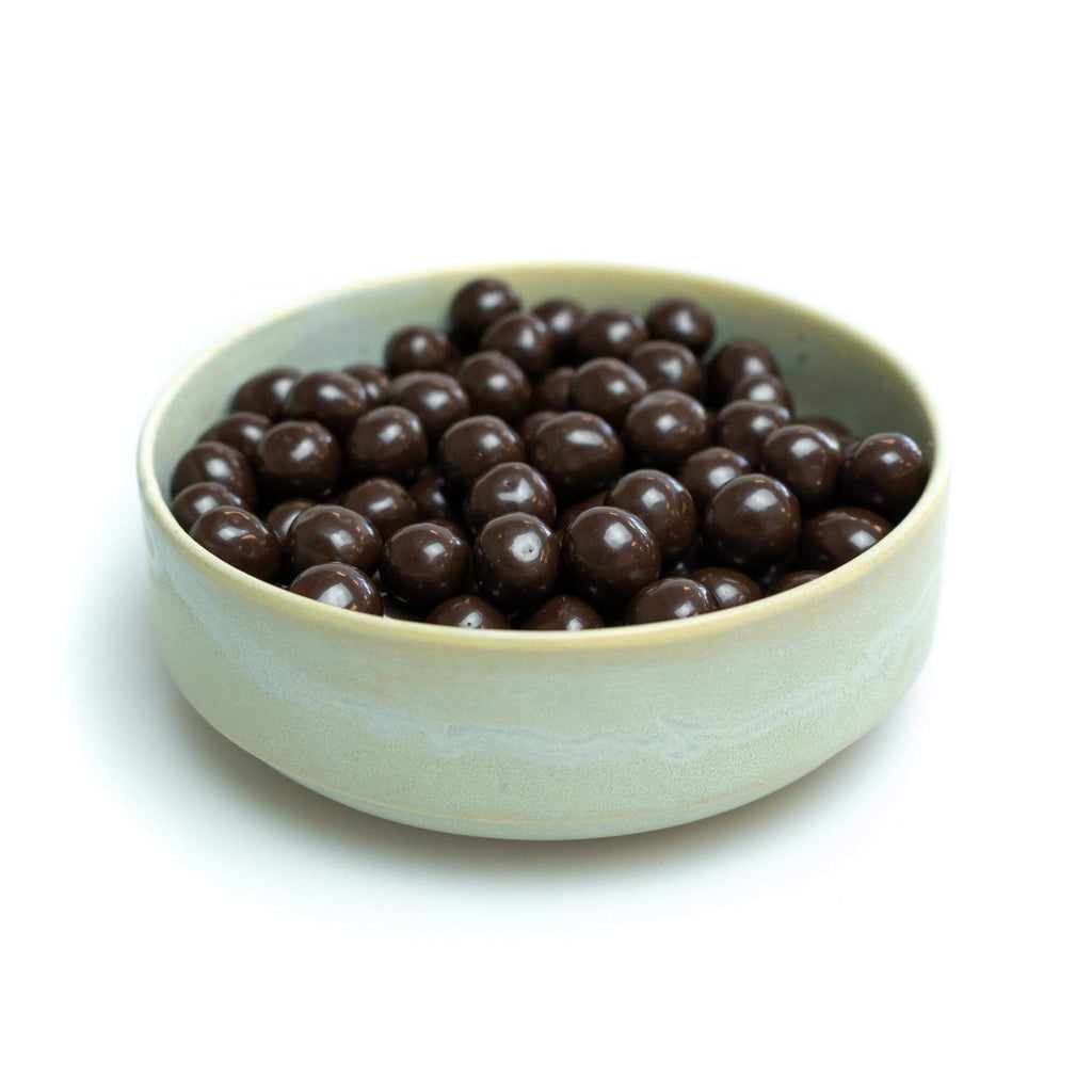Chokoladeovertrukket hasselnødder, billedet er med hvid baggrund taget fra siden.