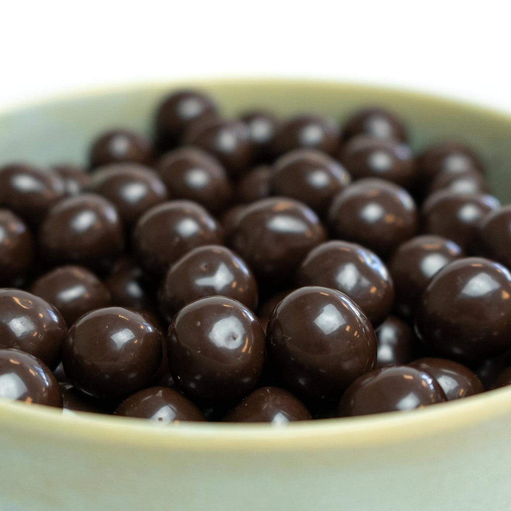 Chokoladeovertrukket hasselnødder, billedet er med hvid baggrund taget fra siden, hvor der er zoomet ind på hasselnødderne.