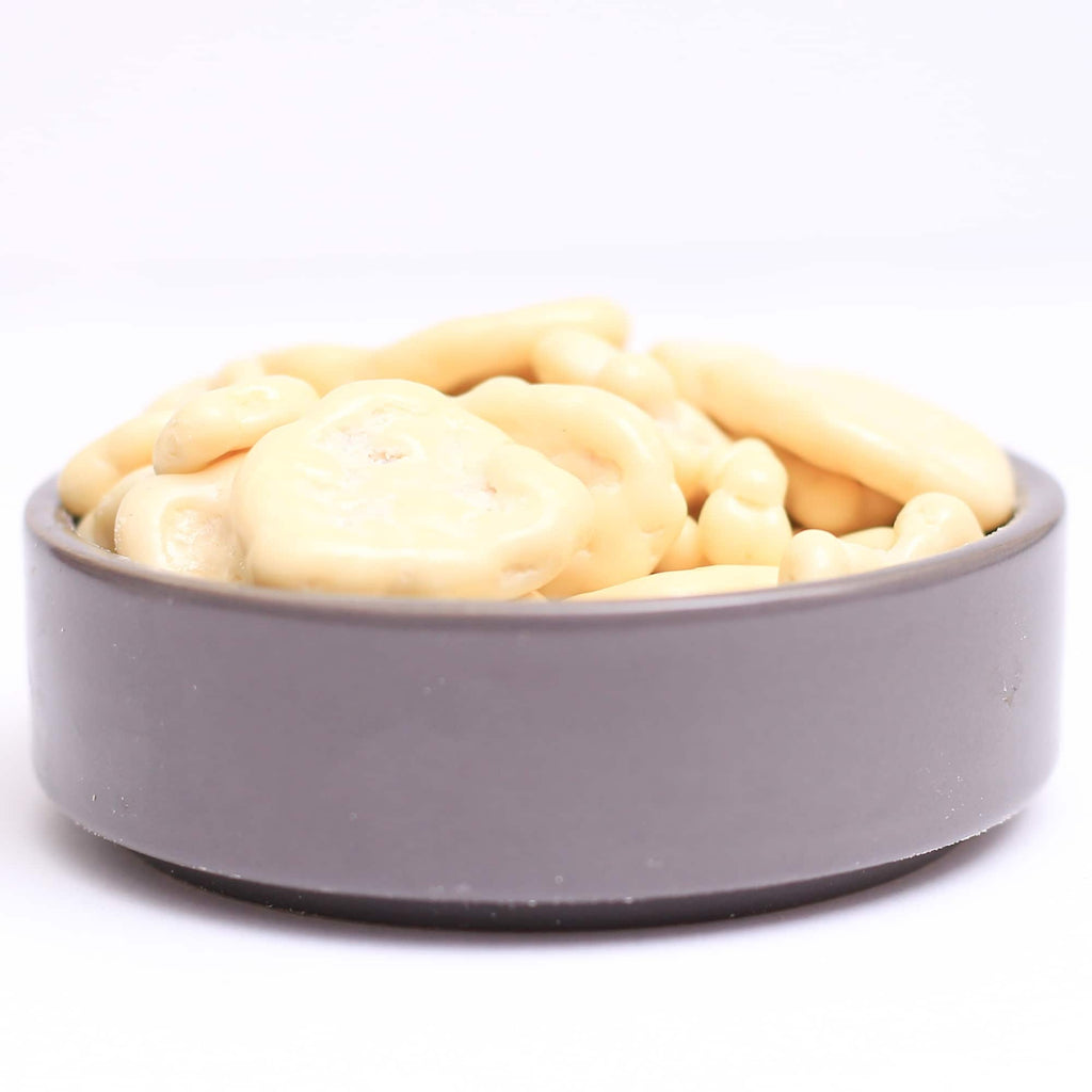Bananchips med hvid chokolade, billedet er med hvid baggrund taget tæt på fra siden, hvor chipsene fylder skålen