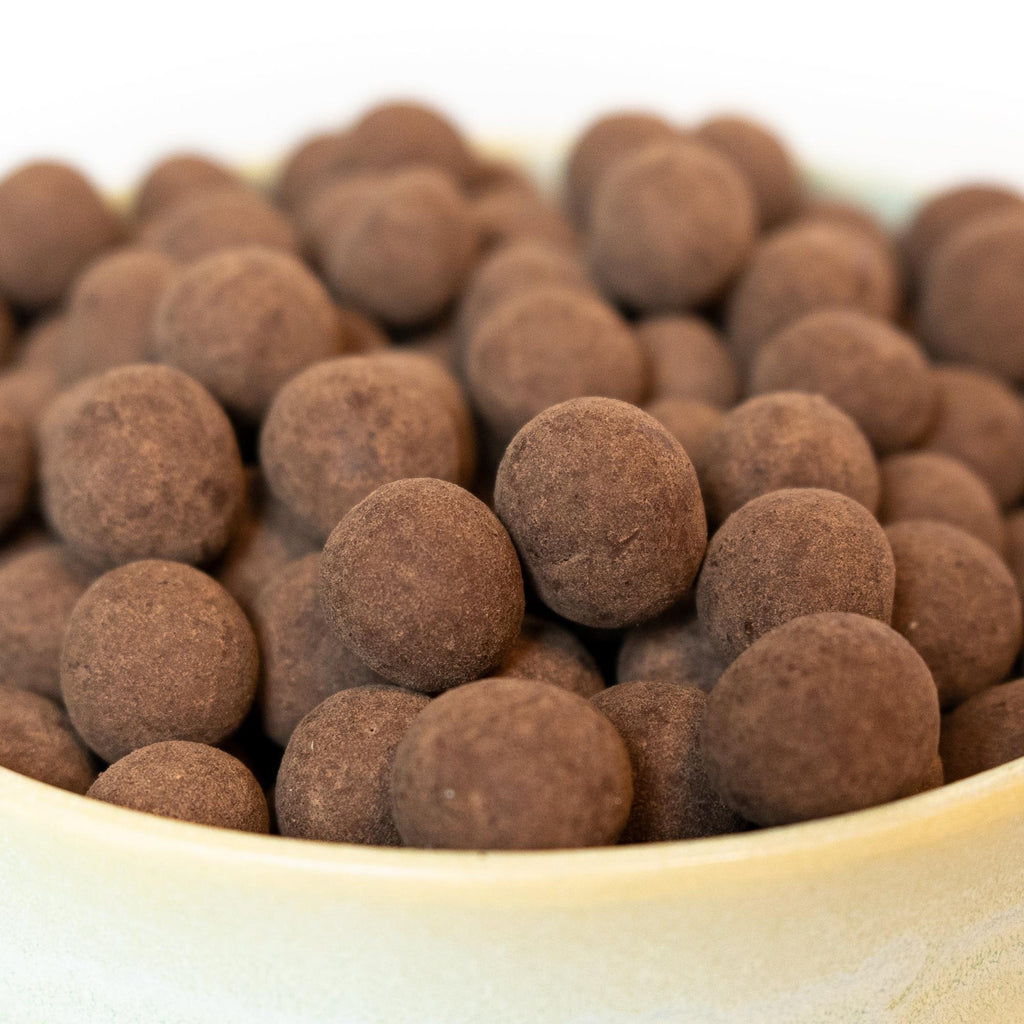Mælkechokoladeovertrukket hasselnødder, billedet er med hvid baggrund taget fra siden, hvor der er zoomet ind på hasselnødderne.